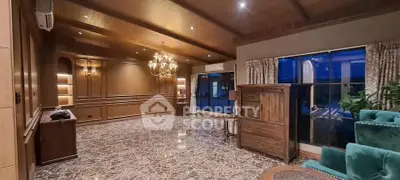 Luxurious living room with elegant wooden paneling and marble flooring, featuring a chandelier and large windows.