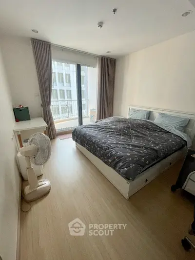 Spacious and well-lit bedroom with large windows offering ample natural light, complemented by elegant drapery and a comfortable bed, perfect for restful nights.