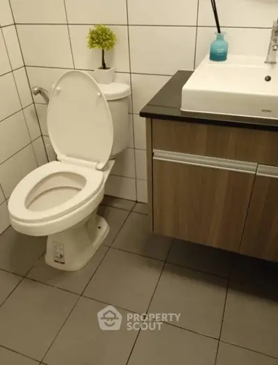 Modern bathroom with sleek fixtures and tiled walls, featuring a stylish vanity and toilet.