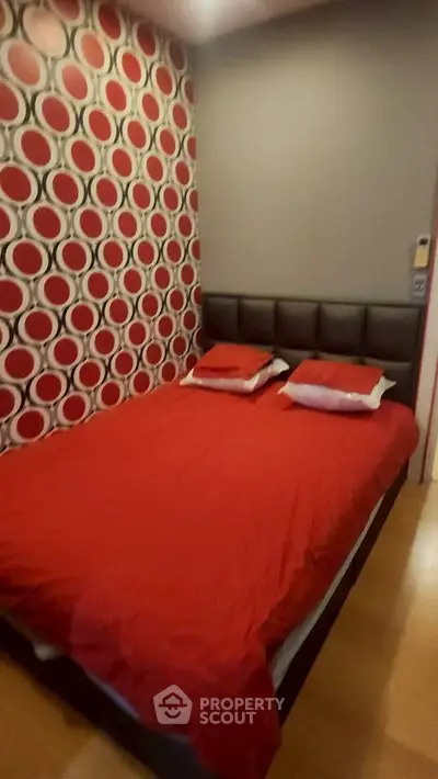 Stylish bedroom with bold patterned accent wall and cozy red bedding