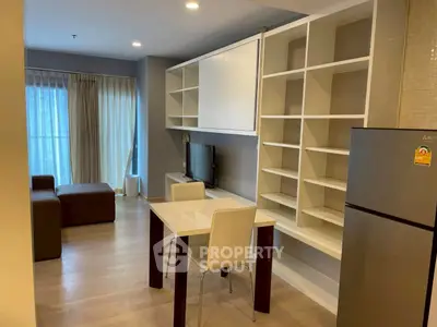 Modern living room with open kitchen, sleek shelving, and cozy seating area.