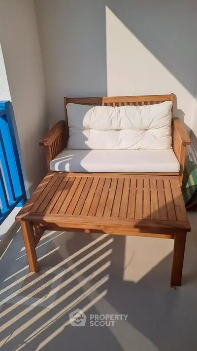 Charming balcony with wooden furniture and blue railing, perfect for relaxation.