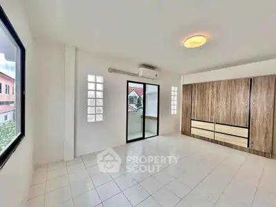 Spacious bedroom with large windows and modern wardrobe in a bright, airy home.