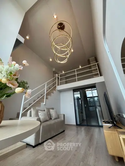 Stunning modern living room with high ceiling and elegant chandelier in a loft-style apartment.