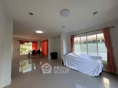 Spacious living room with large windows and natural light, featuring modern decor and tiled flooring.