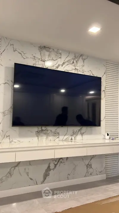 Luxurious living room with marble accent wall and large flat-screen TV, perfect for modern entertainment.