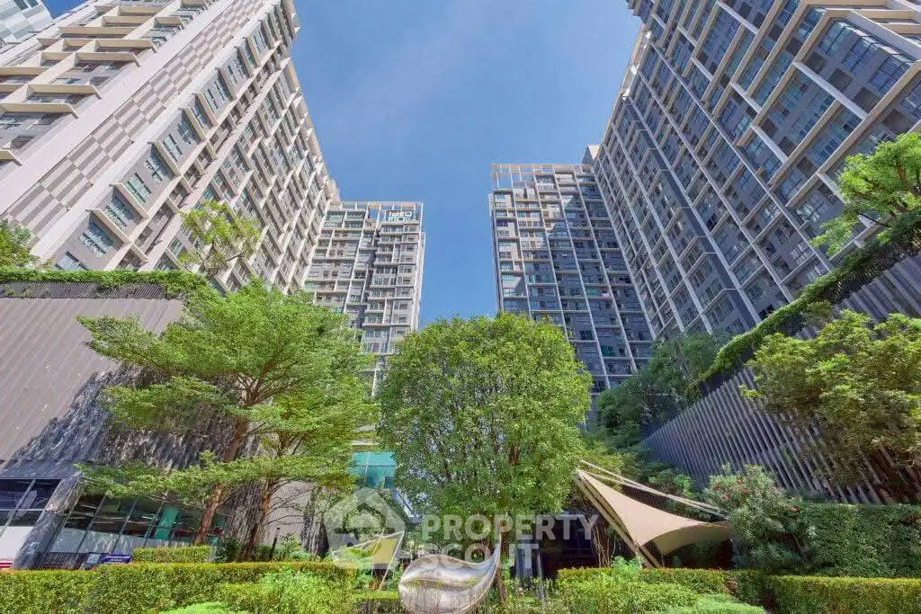 Stunning modern high-rise buildings with lush greenery and clear blue sky.