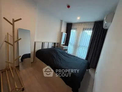 Modern bedroom with sleek design, featuring a large window and minimalist decor for a cozy living experience.