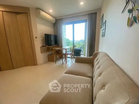 Cozy living room with modern sofa, TV, and balcony view in stylish apartment.