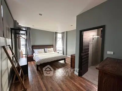 Spacious bedroom with ensuite bathroom and wooden flooring in modern apartment.