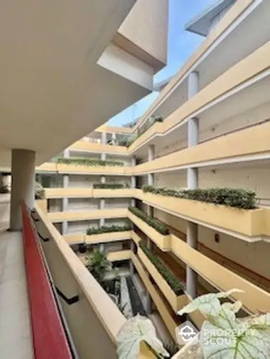 Spacious balcony with a view of a modern multi-level apartment complex, featuring lush greenery and contemporary architecture.