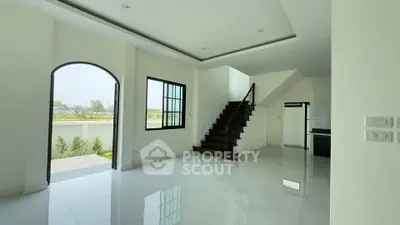 Spacious modern living room with staircase and large windows offering natural light.