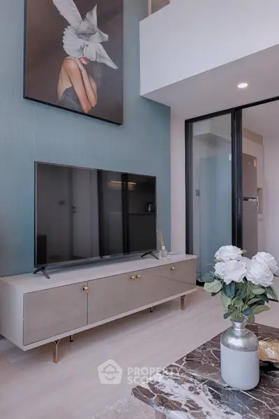 Modern living room with stylish decor and large TV, featuring elegant furniture and contemporary artwork.