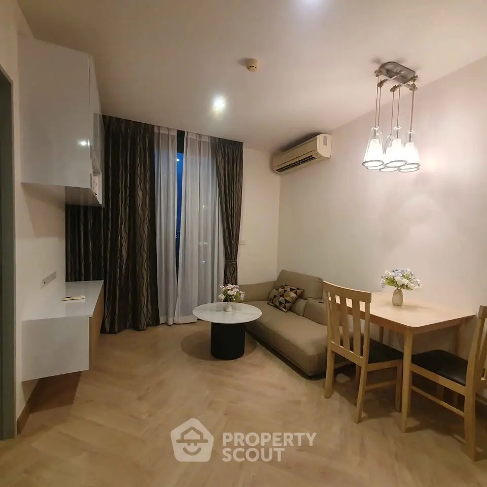 Cozy living room with modern decor and dining area, featuring elegant lighting and air conditioning.