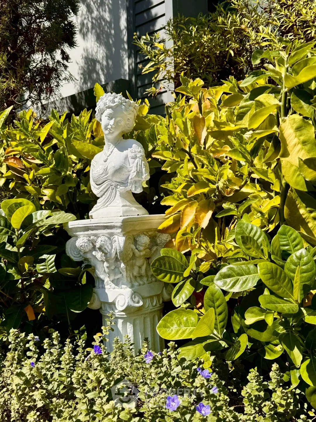 Charming garden with classical statue surrounded by lush greenery, perfect for serene outdoor living.