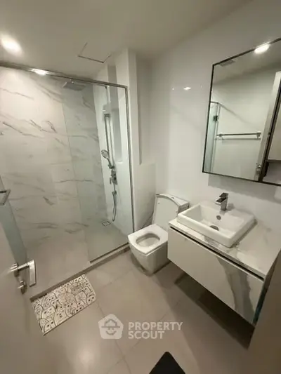 Modern bathroom with glass shower and sleek fixtures in a contemporary apartment.