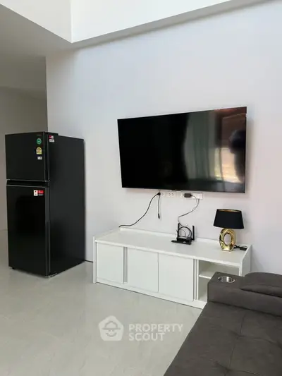 Modern living room with wall-mounted TV and sleek black fridge
