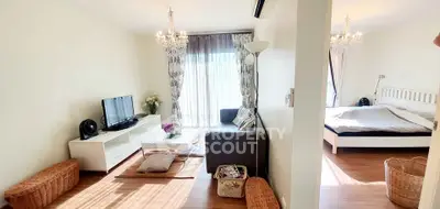Charming open-plan living room and bedroom with elegant chandeliers and cozy decor.