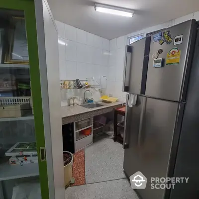 Compact kitchen space with modern stainless steel refrigerator, ample counter space, and built-in oven, ideal for culinary enthusiasts.