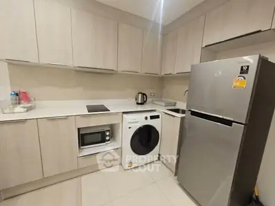 Modern kitchen with sleek cabinetry, washing machine, and stainless steel fridge.