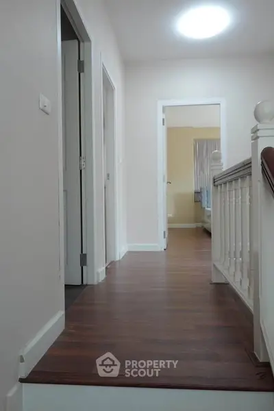 Spacious hallway with wooden flooring and bright lighting in modern home