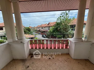 Charming balcony with classic columns overlooking a serene residential street.