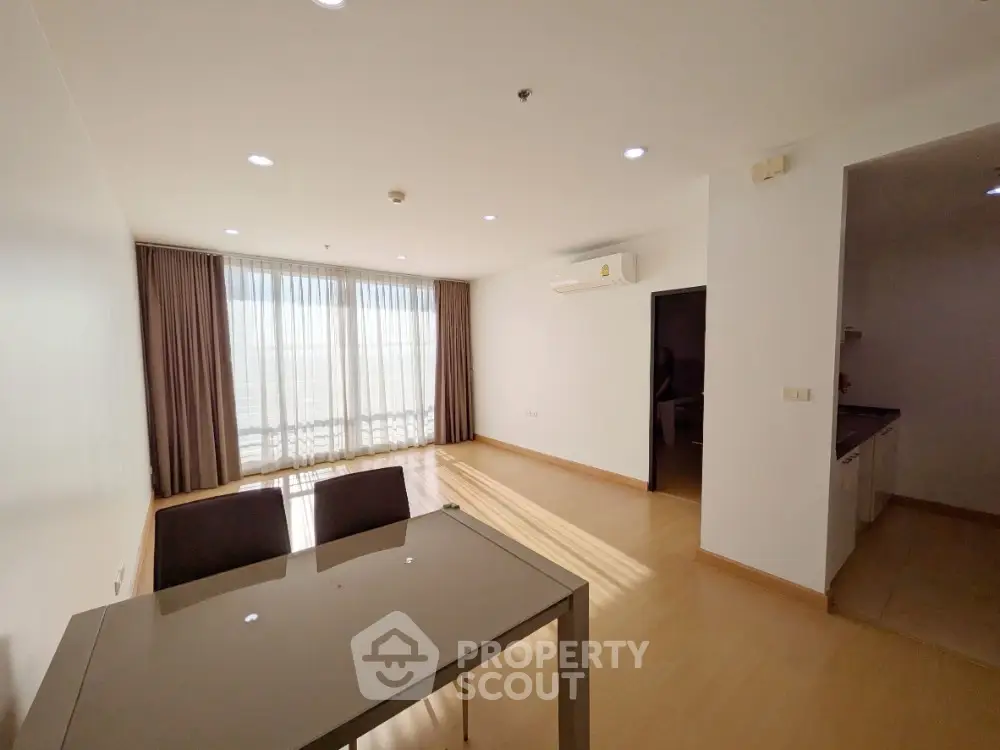 Spacious living room with natural light and modern dining area in a stylish apartment.