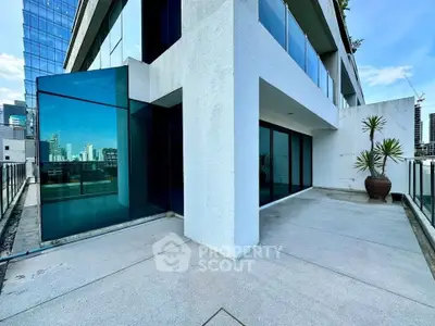 Modern apartment with spacious balcony and city skyline view, featuring sleek glass and concrete design.