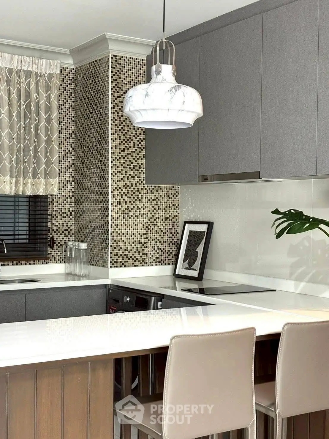 Modern kitchen with sleek cabinetry, marble pendant light, and stylish backsplash, perfect for contemporary living.