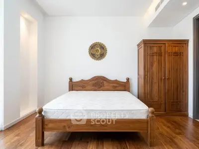 Spacious bedroom with wooden bed and wardrobe, featuring elegant decor and hardwood flooring.