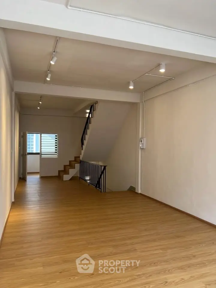 Spacious open-plan living area with wooden flooring and staircase, ideal for modern living.