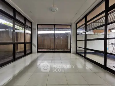 Spacious sunlit room with large windows and tiled flooring, perfect for versatile use.