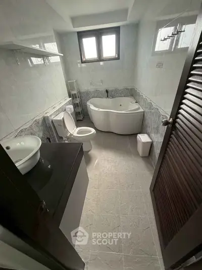 Spacious bathroom with corner bathtub and modern fixtures in a well-lit setting.