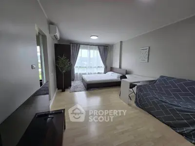 Spacious modern bedroom with large window and stylish decor in a contemporary apartment.