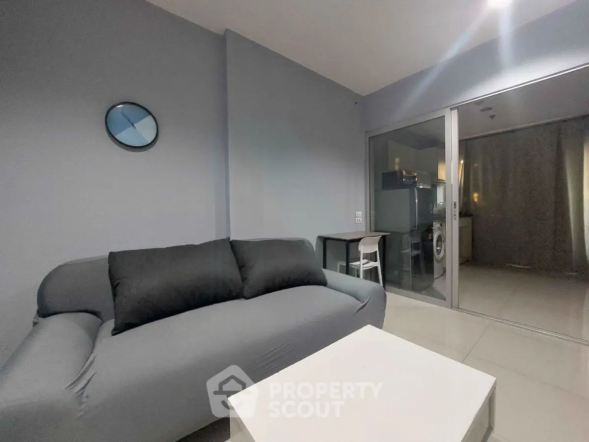 Modern living room with sleek gray sofa and open kitchen layout in a stylish apartment.
