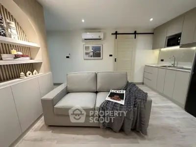 Modern living room with sleek kitchen, cozy sofa, and stylish decor in open layout apartment.
