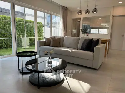 Modern living room with large windows and stylish furniture, offering a bright and inviting atmosphere.