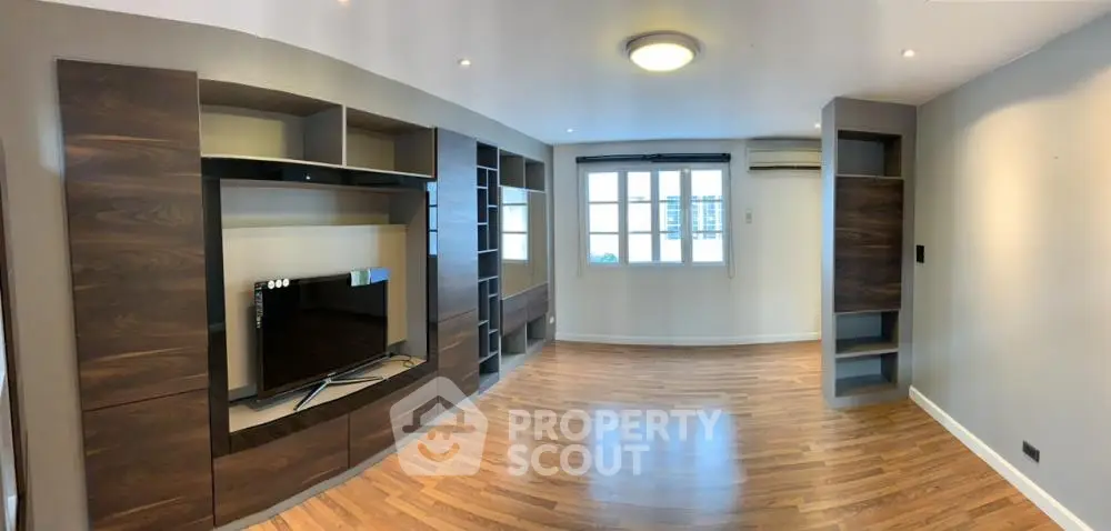 Spacious living room with modern built-in entertainment center and hardwood floors