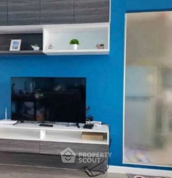 Modern living room with sleek TV unit and vibrant blue accent wall.