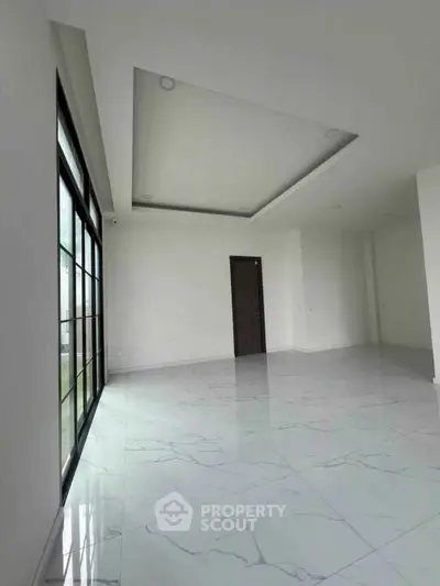 Spacious modern living room with large windows and elegant marble flooring.