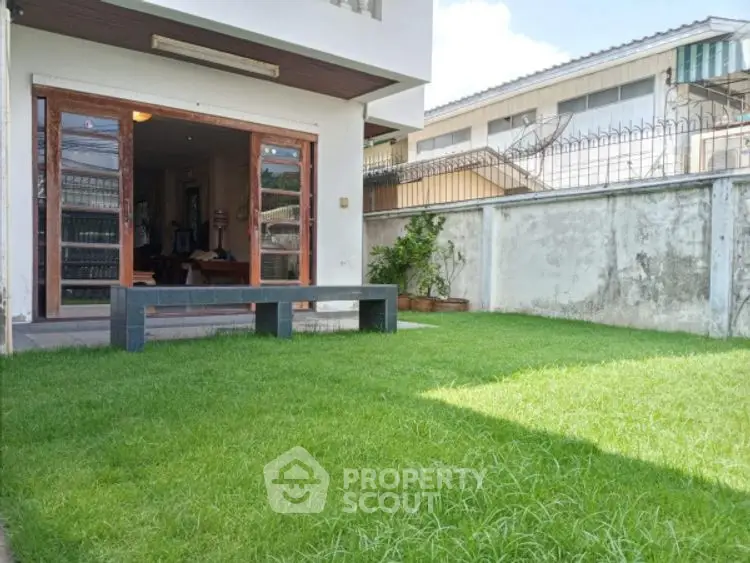 Charming backyard with lush green lawn and patio access in suburban home.