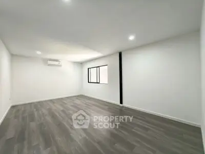 Spacious empty room with wooden flooring and air conditioning, perfect for customization.