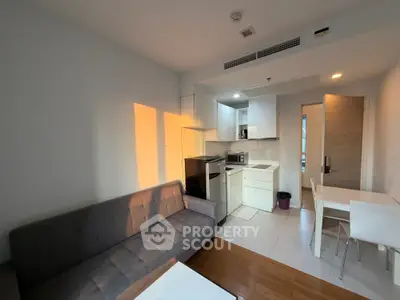 Modern studio apartment with open kitchen and cozy living area, featuring sleek furniture and ample natural light.