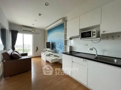 Modern living room with open kitchen, featuring sleek cabinetry and a cozy seating area with a city view.