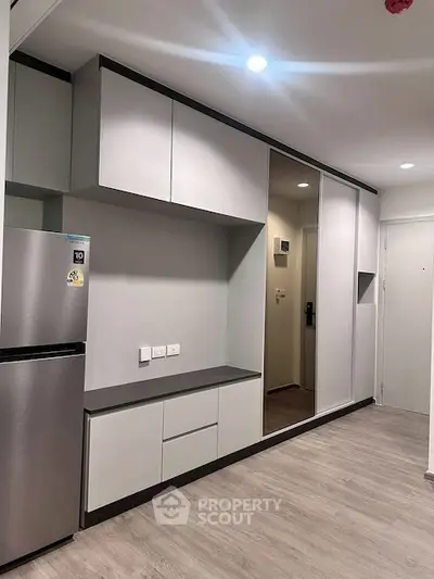 Modern kitchen with sleek cabinetry and stainless steel fridge in a compact apartment.