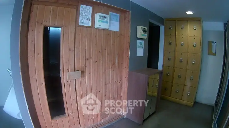 Luxurious sauna room with wooden paneling and secure lockers in modern building.