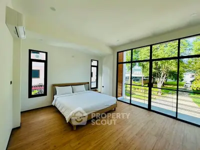 Spacious bedroom with large windows and scenic garden view