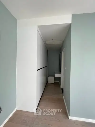 Modern hallway with sleek white storage and light wood flooring in a contemporary home.