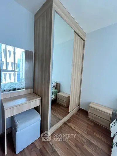 Modern bedroom with wooden wardrobe and vanity set, featuring a sleek design and natural light.