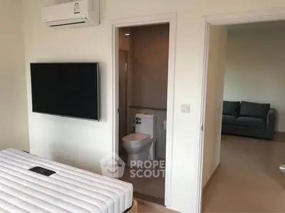 Modern bedroom with wall-mounted TV and ensuite bathroom in a stylish apartment.